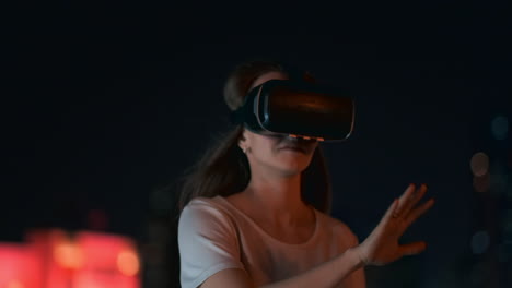 A-young-woman-in-virtual-reality-glasses-in-the-night-city-moves-her-hands-mastering-the-application-interface.-VR-technologies-of-the-future-in-everyday-life.-Virtual-reality-games